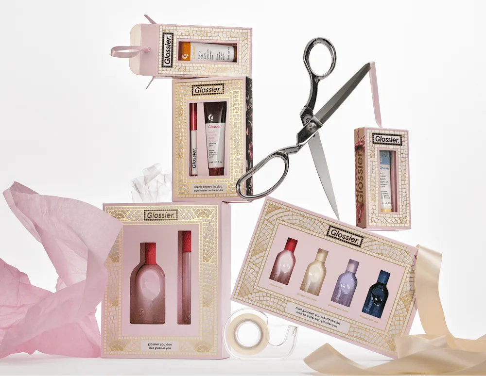 Glossier holiday gifts and beauty essentials wrapped in pink ribbon